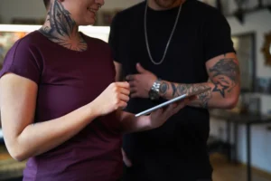 dos personas tatuadas mirando una tablet